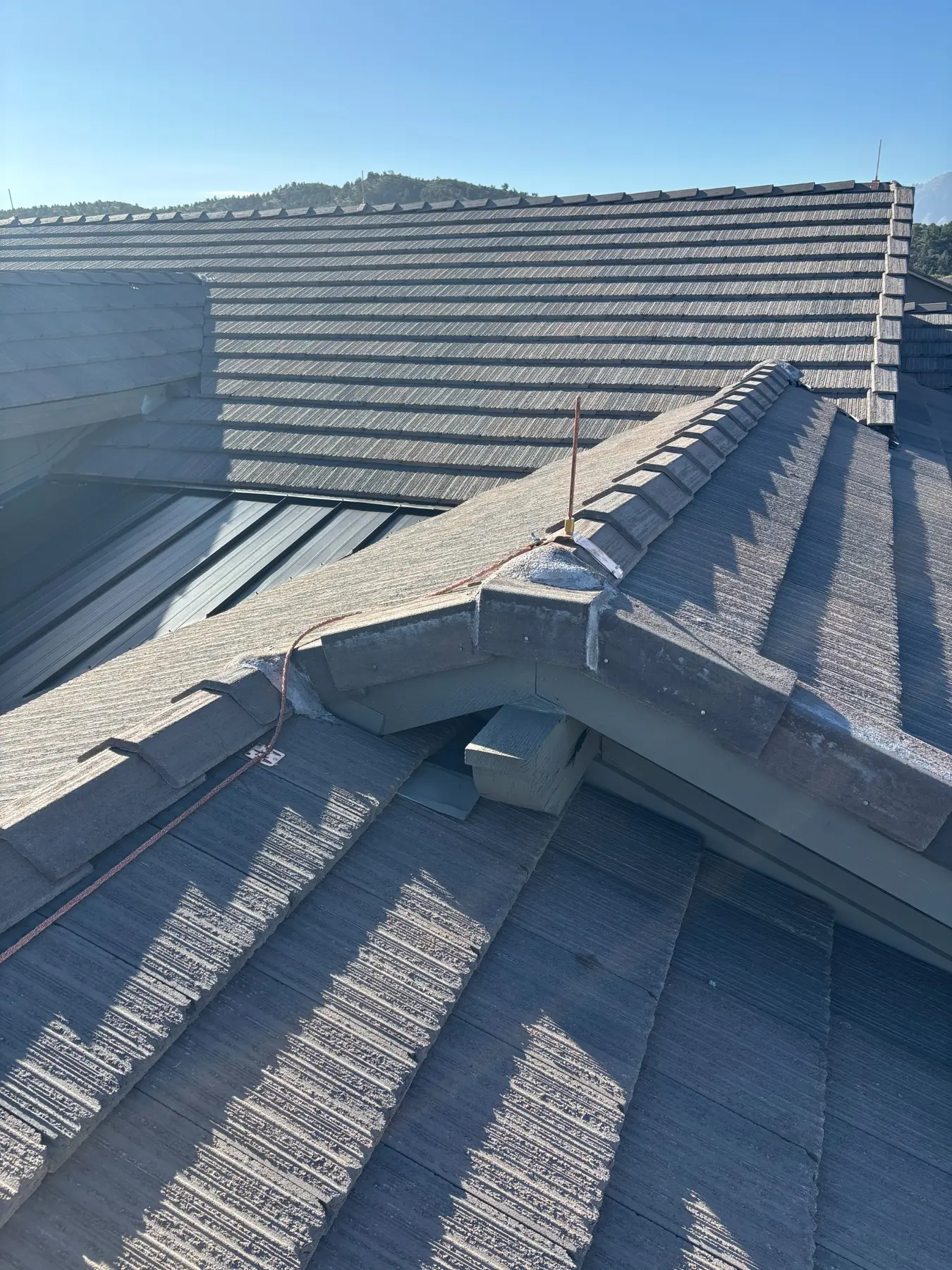 Copper lightning protection conductor installed through a tile roof valley